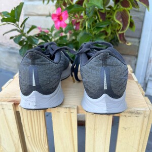 K&ouml;nnte beinhalten: Ein Paar schwarze Nike Laufschuhe mit wei&szlig;er Sohle. Die Schuhe haben ein strukturiertes Obermaterial und ein wei&szlig;es Swoosh-Logo an der Seite.