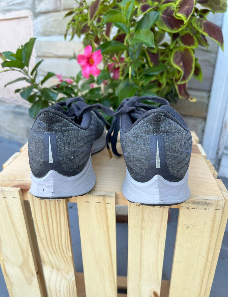 K&ouml;nnte beinhalten: Ein Paar schwarze Nike Laufschuhe mit wei&szlig;er Sohle. Die Schuhe haben ein strukturiertes Obermaterial und ein wei&szlig;es Swoosh-Logo an der Seite.