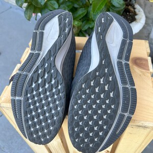 K&ouml;nnte beinhalten: Schwarze Laufschuhe mit einem wei&szlig;en Swoosh-Logo und einem schwarzen und wei&szlig;en Profil.