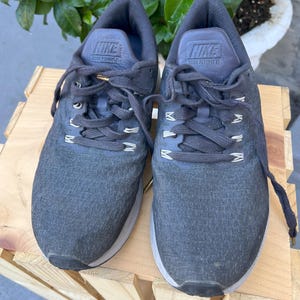 K&ouml;nnte beinhalten: Ein Paar graue Nike Laufschuhe mit schwarzen Schn&uuml;rsenkeln und dem Text "Zoom Pegasus 35" auf der Zunge.