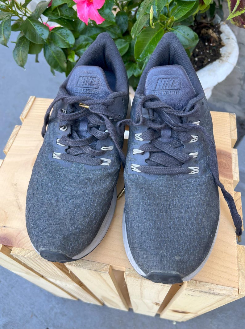 K&ouml;nnte beinhalten: Ein Paar graue Nike Laufschuhe mit schwarzen Schn&uuml;rsenkeln und dem Text "Zoom Pegasus 35" auf der Zunge.