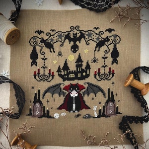 May include: Cross stitch pattern featuring a black cat dressed as a vampire with a red cape, a haunted house, bats, and candles. The pattern is titled "Dracula" and is available on Etsy from Stitch with Coffee Designs.