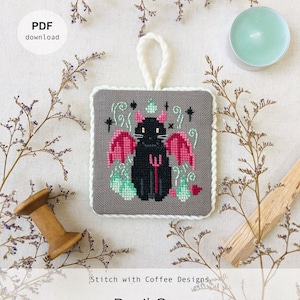 May include: A cross-stitch pattern featuring a black cat with red devil wings and a pitchfork. The pattern is on a gray background with green and pink accents. The text "Devil Cat" is below the pattern. The text "Stitch with Coffee Designs" is above the pattern. The text "www.stitchwithcoffee.etsy.com" is below the text "Devil Cat".