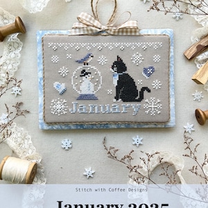 May include: Cross stitch pattern for January from the Monthly Kitty Calendar Series 2025. The design features a black cat, a snowman in a snow globe, and a bluebird. The words "January" are stitched below the design.