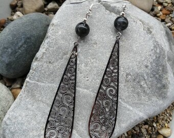 May include: A pair of silver dangle earrings with black gemstone beads and intricate filigree designs.