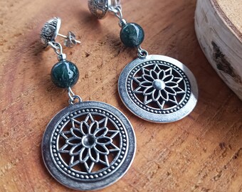 May include: A pair of silver earrings with a green stone bead and a circular pendant featuring a cutout floral design.