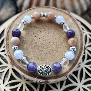 Op de afbeelding: Een armband gemaakt met amethist, sunstone, heldere kwarts en blauwe kwarts. De armband heeft een zilveren bedel met een bloemmotief.
