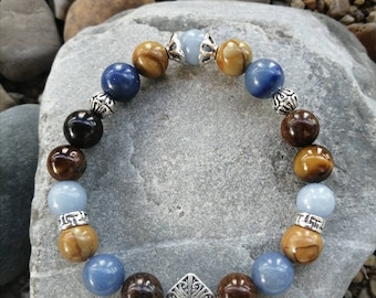 May include: A beaded bracelet with brown, blue, and light blue stones, silver accents, and a silver charm with a geometric design.