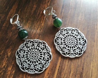 May include: A pair of silver earrings with a filigree design and a green stone bead on each earring.