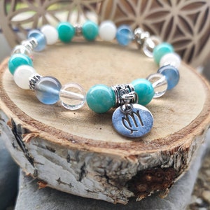 Peut inclure: Un bracelet en perles turquoise et blanches avec un charme en argent représentant le symbole du zodiaque Vierge.