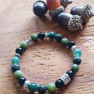 Peut inclure: Un bracelet en perles vertes et noires avec des accents argentés. Le bracelet est composé de perles de jade vert, d'onyx noir et de lave.