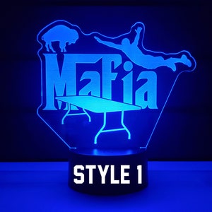 May include: Blue LED night light with a silhouette of a person jumping over a table, a buffalo, and the word "Mafia". The base of the light is black with the words "STYLE 1" in white.