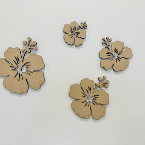 Peut inclure: Quatre fleurs d'hibiscus d&eacute;coup&eacute;es en bois brun sur un fond blanc.