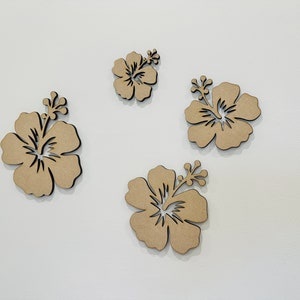 Peut inclure: Quatre fleurs d'hibiscus d&eacute;coup&eacute;es en bois brun sur un fond blanc.