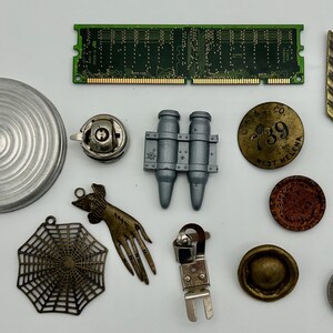 May include: A collection of vintage and antique items, including a silver-colored metal lid, a green circuit board, a silver-colored metal object with a circular design, a silver-colored metal object with a hand-shaped design, a silver-colored metal object with a spiderweb design, a silver-colored metal object with a bullet-shaped design, a gold-colored metal object with a circular design and the text "O.R. & S. CO. 739 WEST HELENA", a gold-colored metal object with an arrow-shaped design, a brown leather object with a circular design, a silver-colored metal object with a circular design, a silver-colored metal object with a circular design, a silver-colored metal object with a circular design, and a silver-colored metal watch with a white face.