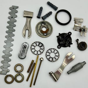 May include: Assortment of metal and plastic hardware parts, including springs, gears, washers, and screws. The parts are arranged on a white surface.