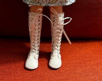 May include: White lace-up boots with a rounded toe and a white ribbon tied around the ankle.