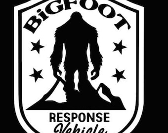 Peut inclure: Autocollant blanc en forme de bouclier avec une silhouette noire de Bigfoot debout sur une montagne. Le texte "BIGFOOT RESPONSE VEHICLE" est écrit en blanc, en gras.