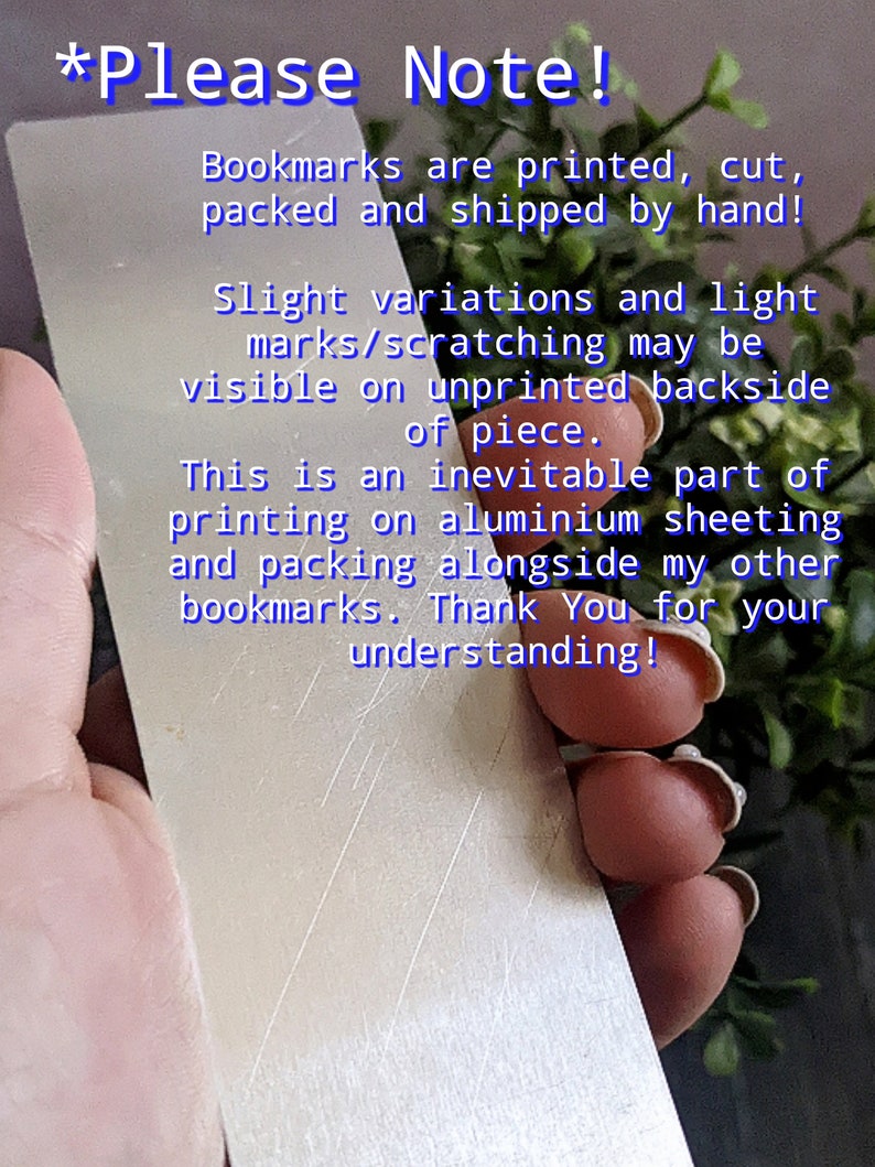 May include: Close-up of a silver bookmark with a hand holding it. The bookmark has a message that reads "*Please Note! Bookmarks are printed, cut, packed and shipped by hand! Slight variations and light marks/scratching may be visible on unprinted backside of piece. This is an inevitable part of printing on aluminium sheeting and packing alongside my other bookmarks. Thank You for your understanding!"