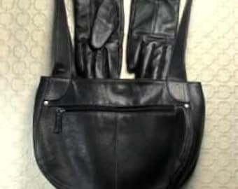 Puede incluir: Mochila de cuero negro con base curva y bolsillo frontal con cremallera. Dos guantes de cuero negro están sujetos a las correas de la mochila. Los guantes son talla mediana.