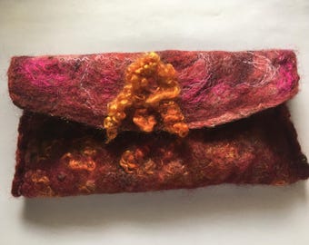 May include: A small, red and orange felted clutch purse with a decorative orange wool flower embellishment.