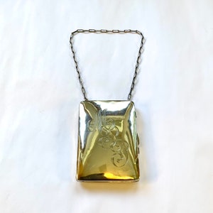 May include: A silver locket with a chain, engraved with a monogram. The locket is closed and has a polished finish.