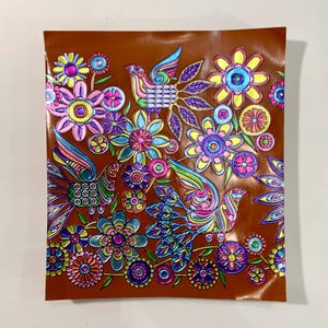 May include: A brown background with a colorful floral and bird design. The design features pink, blue, green, yellow, and purple flowers with intricate details. There are three birds with colorful wings and bodies.