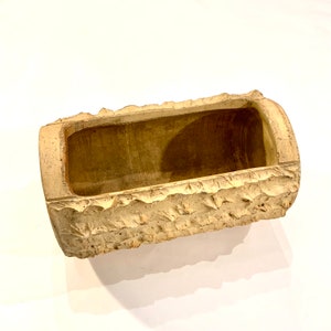May include: A light brown ceramic planter shaped like a log with a rough, textured surface.