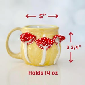 May include: A yellow ceramic mug with three red and white mushroom accents. The mug holds 14 ounces and measures 5 inches wide and 3 3/4 inches tall.