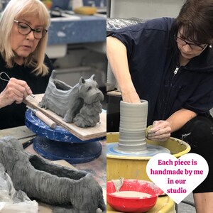 May include: Two women working with clay in a pottery studio. One woman is shaping a clay dog sculpture, while the other is using a pottery wheel to create a tall, cylindrical vase. The text "Each piece is handmade by me in our studio" is visible in the image.