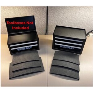 May include: Two black Kobalt toolboxes with silver drawer handles. One toolbox is open, displaying the text Toolboxes Not Included in red. Each unit is accompanied by three black foam drawer liners with a textured surface and curved edges.