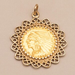 May include: A gold pendant with a coin depicting an Indian head profile, encased in a decorative filigree frame. The pendant includes a loop for a chain and is a vintage item. The coin is dated 1928.