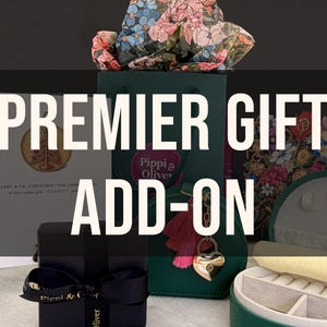 May include: An assortment of gift packaging, including a dark green gift bag with a heart-shaped lock charm and a black box tied with a ribbon. The text "PREMIER GIFT ADD-ON" is displayed prominently.
