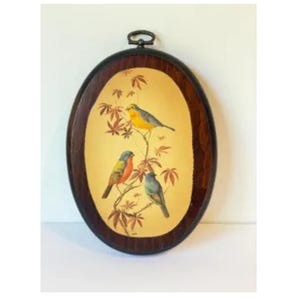 May include: An oval wall plaque featuring a dark brown wooden frame with a hanging loop at the top. The center panel is cream-colored and displays a painted illustration of three small birds perched on thin branches with reddish-brown leaves.