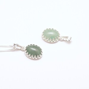 Puede incluir: Dos collares colgantes de plata con piedras preciosas ovaladas de color verde claro. Las piedras est&aacute;n engastadas en un engaste decorativo plateado en forma de corona. Un collar se muestra con su cadena, el otro por separado.