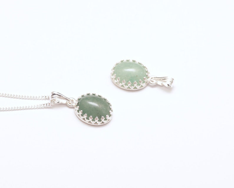 Puede incluir: Dos collares colgantes de plata con piedras preciosas ovaladas de color verde claro. Las piedras est&aacute;n engastadas en un engaste decorativo plateado en forma de corona. Un collar se muestra con su cadena, el otro por separado.