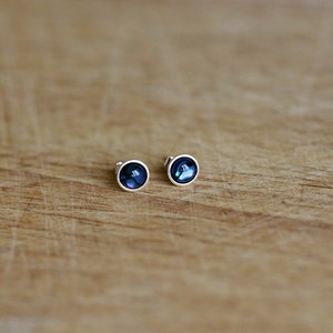 Könnte beinhalten: Ein Paar silberne Ohrstecker mit runden, blauen Abalone-Muscheleinlagen.