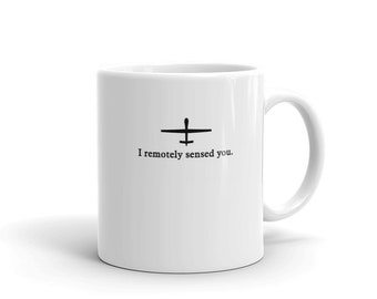 Könnte beinhalten: Eine weiße Keramiktasse mit einer schwarzen Silhouette einer Drohne und dem Text "I remotely sensed you."