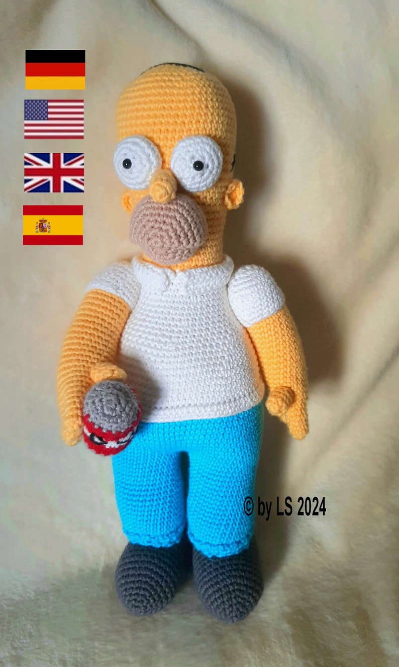 May include: Handmade crochet doll of Homer Simpson, featuring a yellow head, white eyes, and a beige mustache. He wears a white shirt, blue pants, and gray shoes. The doll holds a gray ball with red accents. The text "&copy; by LS 2024" is visible.
