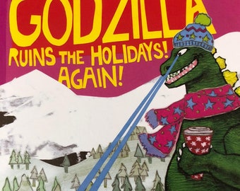 May include: A green Godzilla monster wearing a blue and white winter hat and a pink scarf with white stars is holding a red and white mug. Godzilla is standing in a snowy winter scene with a snowman and three people in the foreground. The text "GODZILLA RUINS THE HOLIDAYS! AGAIN!" is at the top of the image.