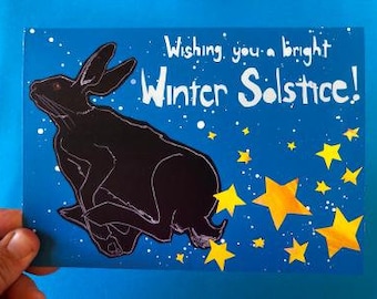 May include: A greeting card with a black rabbit silhouette against a blue background with yellow stars. The card reads "Wishing you a bright Winter Solstice!"