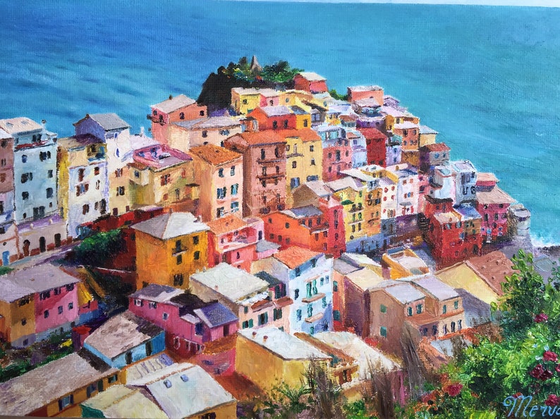 May include: A colourful painting of a seaside town with buildings stacked on top of each other. The buildings are painted in shades of yellow, orange, red, pink, blue, and green. The sea is a bright blue and the sky is a light blue.
