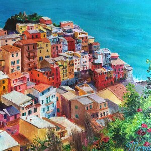 May include: A colourful painting of a hillside village overlooking a turquoise ocean. The houses are painted in shades of yellow, orange, red, pink, and blue. Lush green foliage is in the foreground.