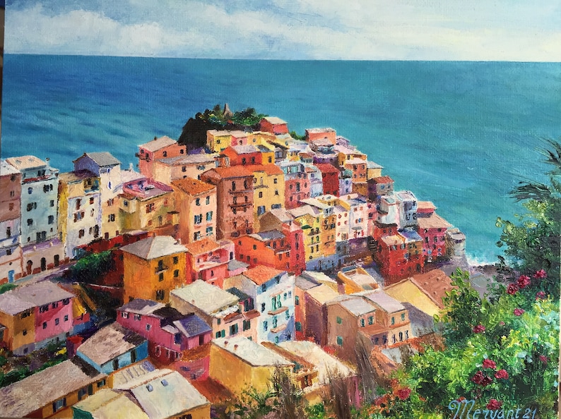 May include: A colourful painting of a seaside town with buildings clustered together on a hillside overlooking the ocean. The sky is blue with white clouds and the water is a bright turquoise.