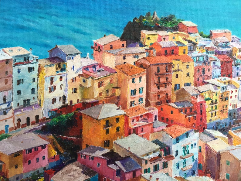 May include: A colourful painting of a seaside town with buildings in shades of yellow, orange, red, pink, and blue. The buildings are clustered together on a hillside overlooking a blue body of water.