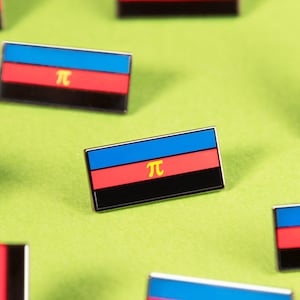 May include: Nine enamel pins featuring a blue, black, and red flag with a yellow "π" symbol. The pins are arranged on a green surface.