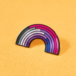 Op de afbeelding: Een regenboogkleurige emaille pin in de vorm van een boog, met kleuren waaronder paars, wit, roze, blauw en zwart.