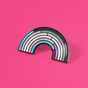 May include: A rainbow-colored enamel pin with a black outline. The pin is shaped like a rainbow arch with multiple stripes of different colors, including pink, blue, white, and purple.