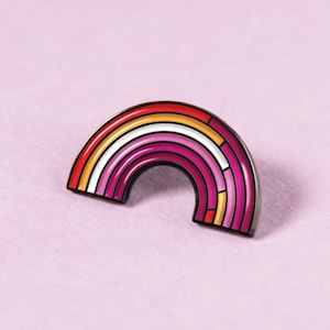 Puede incluir: Un pin de esmalte con forma de arcoíris, que representa la bandera del orgullo lésbico. El pin tiene rayas de rojo, naranja, amarillo, blanco, rosa y rojo oscuro.