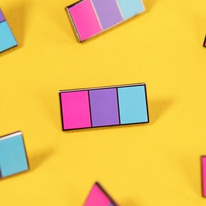 Peut inclure: Dix épingles en émail avec un design tricolore. Les épingles sont roses, violettes et bleues. Les épingles sont éparpillées sur un fond jaune.